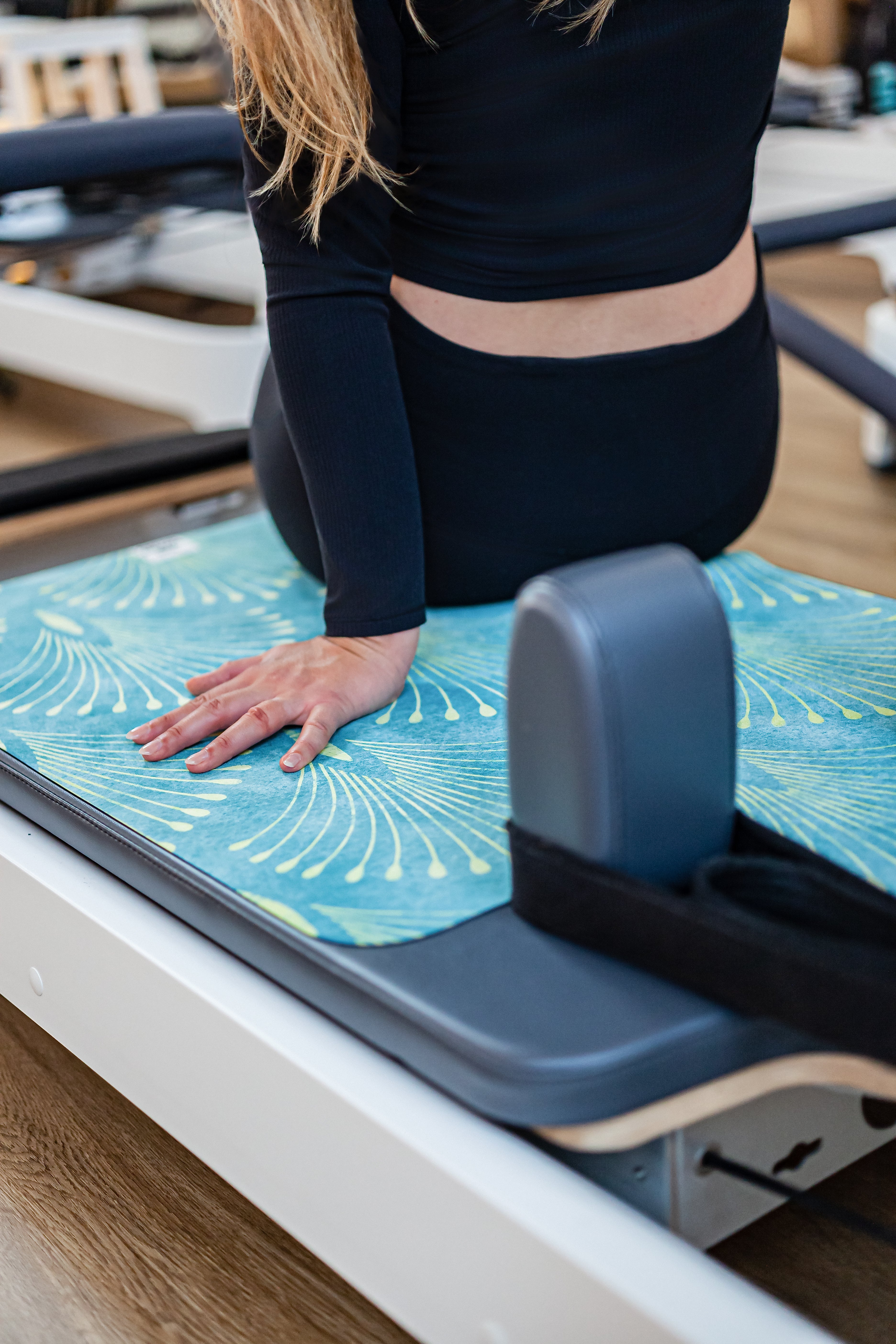 Frau macht Uebung auf Reformer-Matte auf Reformer-Geraet